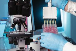 Preimplantation Genetic Diagnosis: Lab technician depositing samples in vials next to microscope